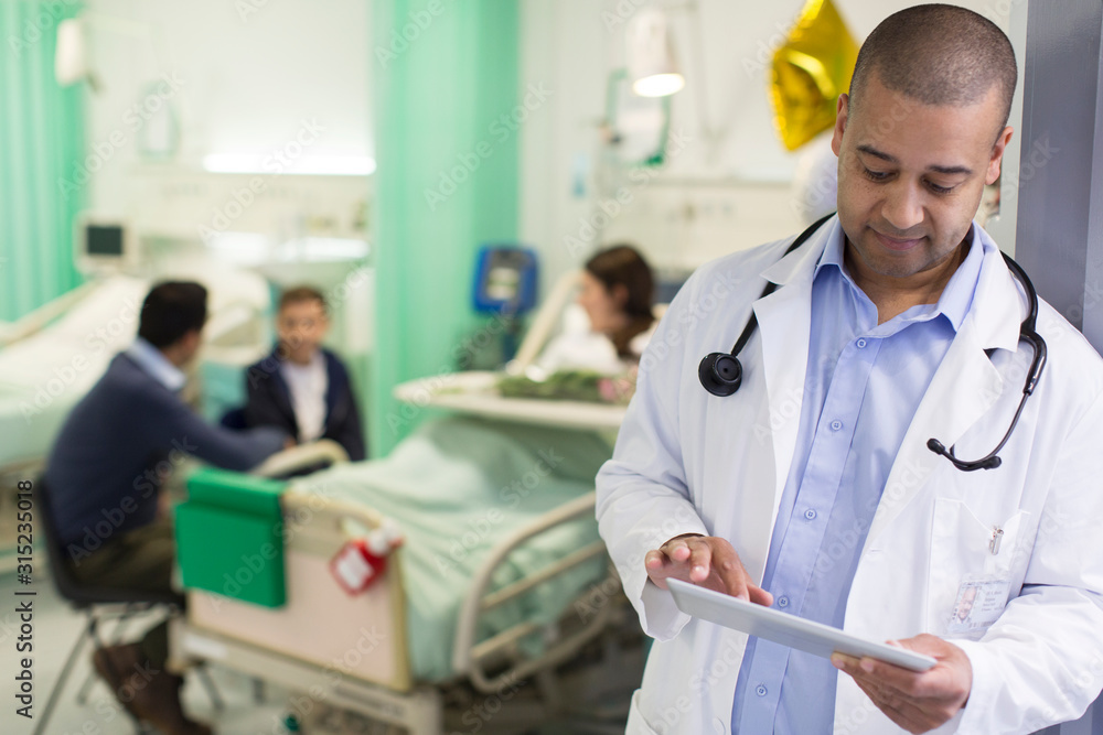 Male doctor with digital tablet making rounds in hospital ward Male doctor with digital tablet making rounds in hospital ward