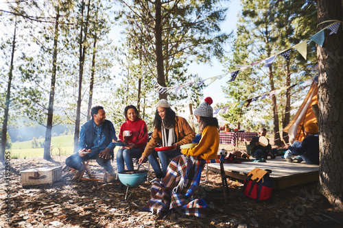 Family cooking at campsite grill in sunny woods photo