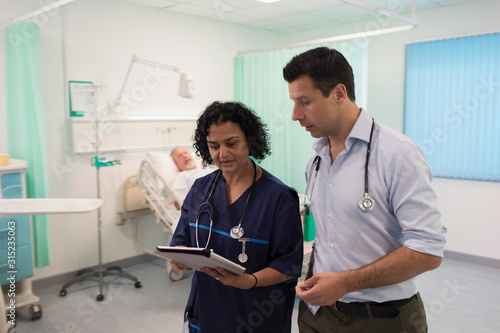 Doctors with digital tablet making rounds, consulting in hospital room