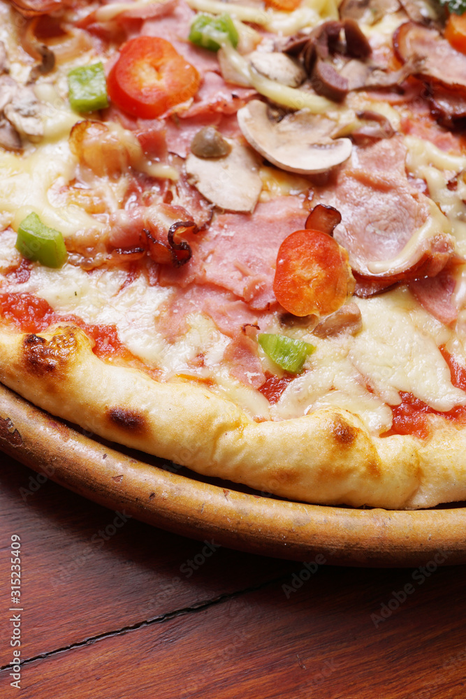 Whole pizza with prosciutto and bacon on wooden background Whole pizza with prosciutto and bacon on wooden background