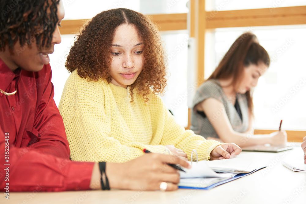 Focused college students studying together in classroom Focused college students studying together in classroom