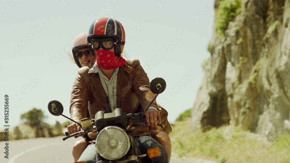 Young couple riding motorcycle on sunny road