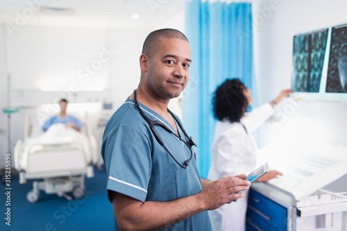 Portrait confident, smiling doctor using digital tablet in hospital room photo