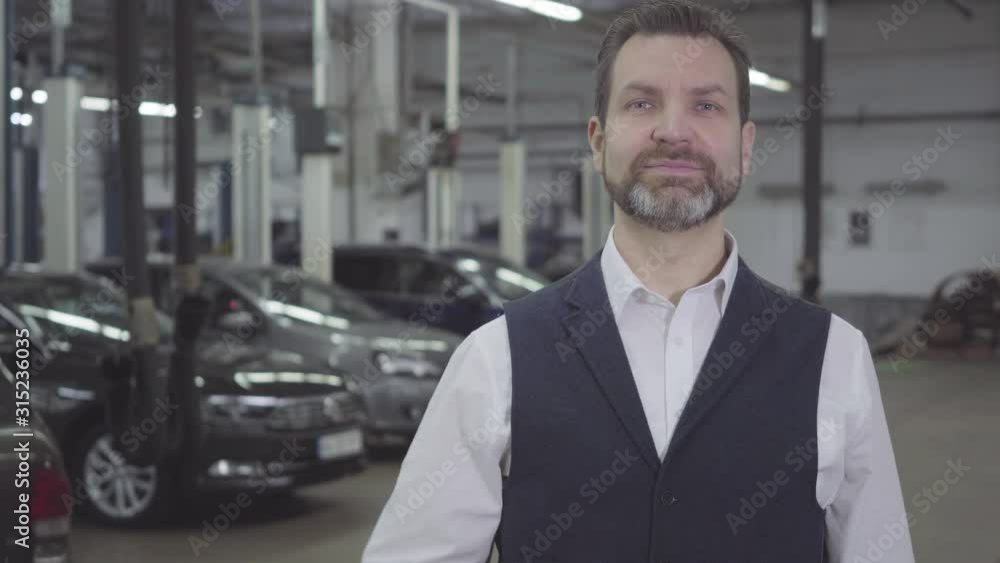 Portrait of confident successful Caucasian man holding car keys in right hand and looking at camera. Automobile owner taking back vehicle after repair. Warranty service, car business. Portrait of confident successful Caucasian man holding car keys in right hand and looking at camera. Automobile owner taking back vehicle after repair. Warranty service, car business.