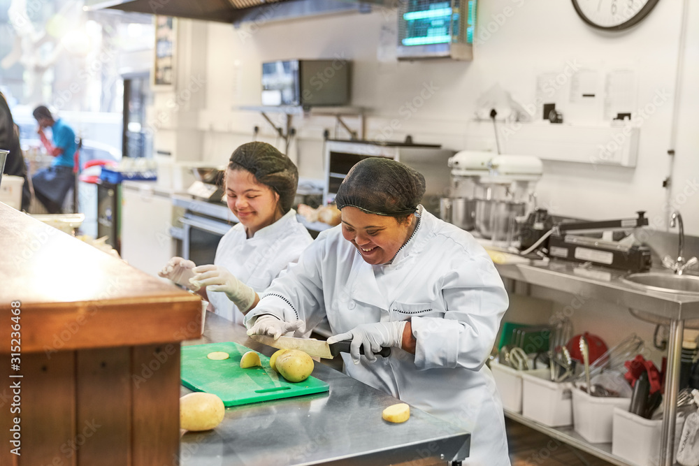 Happy young women with Down Syndrome cooking in cafe Happy young women with Down Syndrome cooking in cafe