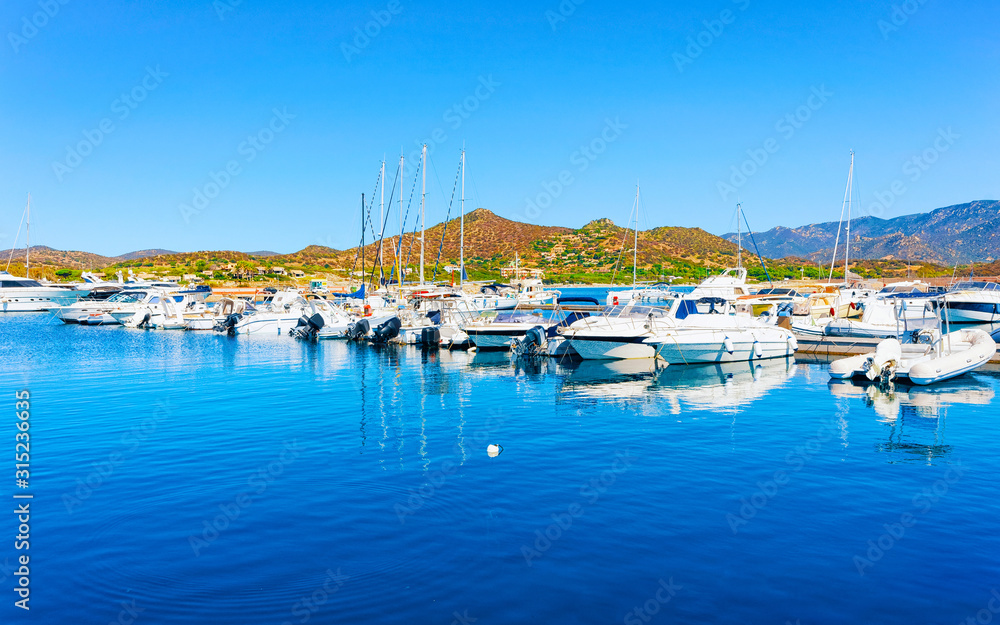 Old Sardinian Port and marina with ships at Mediterranean Sea in city of Villasimius in South Sardinia Island Italy in summer. Cityscape with Yachts and boats