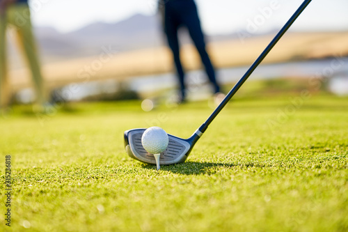 Close up golfer preparing to tee off at sunny tee box