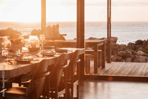 Sunny home showcase dining room overlooking ocean at sunset