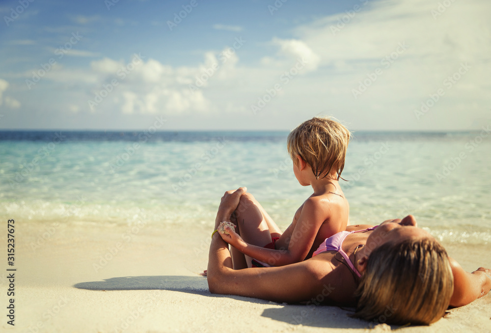 Mother and son laying and relaxing on tropical beach Mother and son laying and relaxing on tropical beach