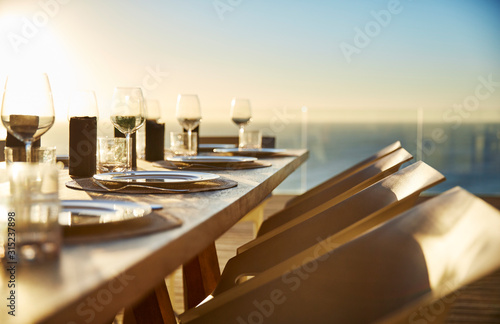 Sunset behind placesettings on luxury patio dining table photo