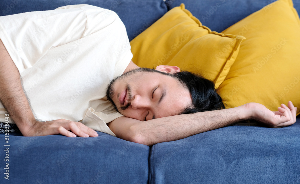 Young handsome asian man sleeping on sofa at home living room, people lifestyle
