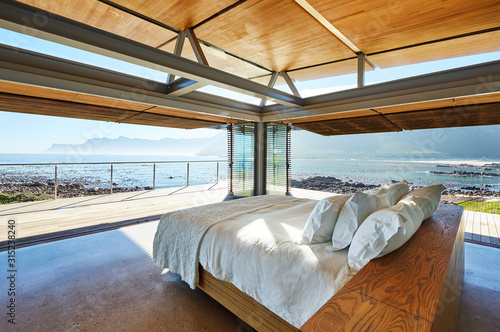 Modern luxury bed open to patio with sunny ocean view photo