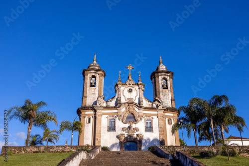 Our Lady of Carmo church in historic colonial city centre of Ouro Preto with palm trees to the side and stairway leading up to the exterior facade and entrance