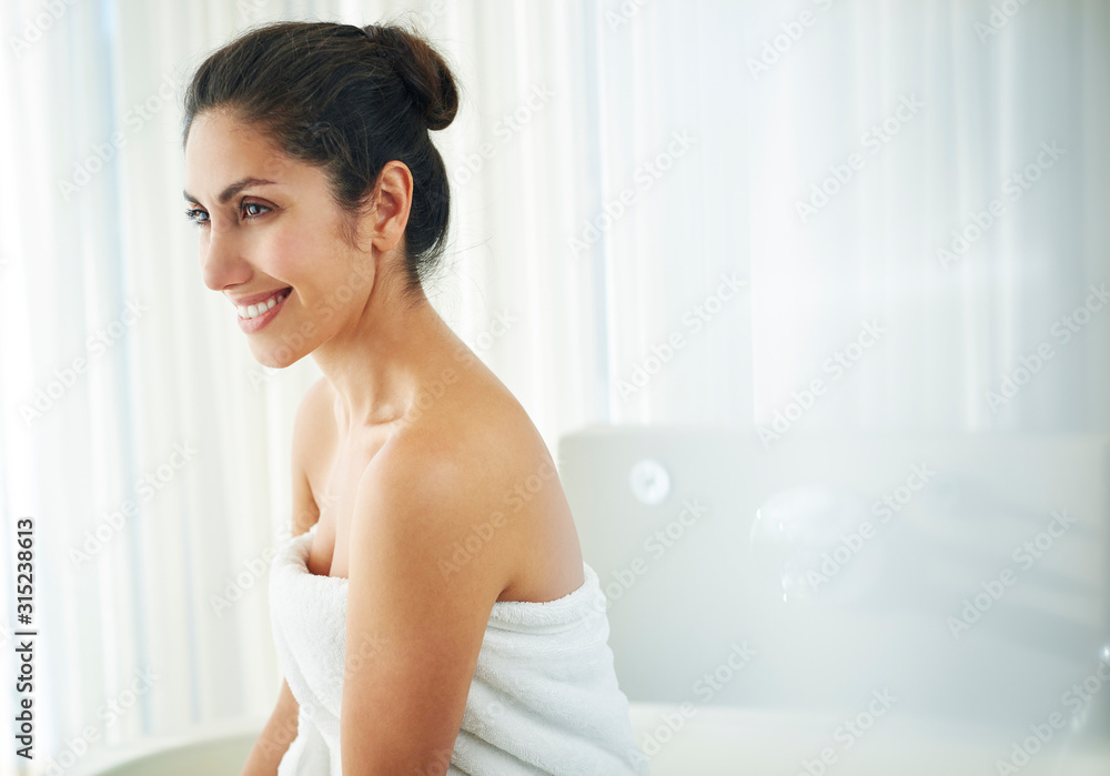 Smiling brunette woman wrapped in towel looking away Smiling brunette woman wrapped in towel looking away
