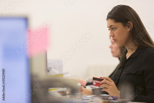 Focused businesswoman with credit card at computer in office photo