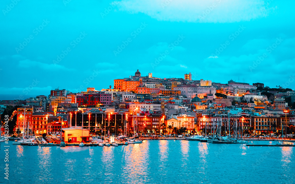 Fototapeta premium Old Sardinian Port with ships at Mediterranean Sea and city of Cagliari, South Sardinia Island in Italy in summer. Cityscape with marina and Yachts and boats in town