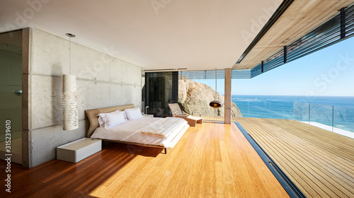 Modern luxury bedroom open to patio with sunny ocean view photo