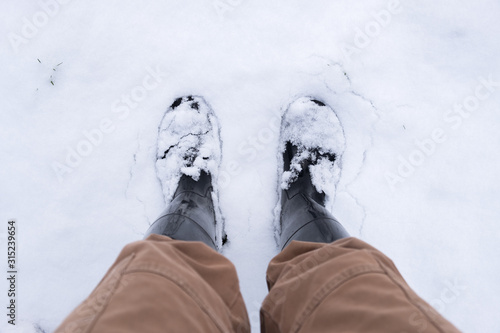 Looking down on pants and snow-covered boots from first-person point of view