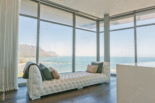 Tufted chaise lounge at luxury home showcase interior window with ocean view photo