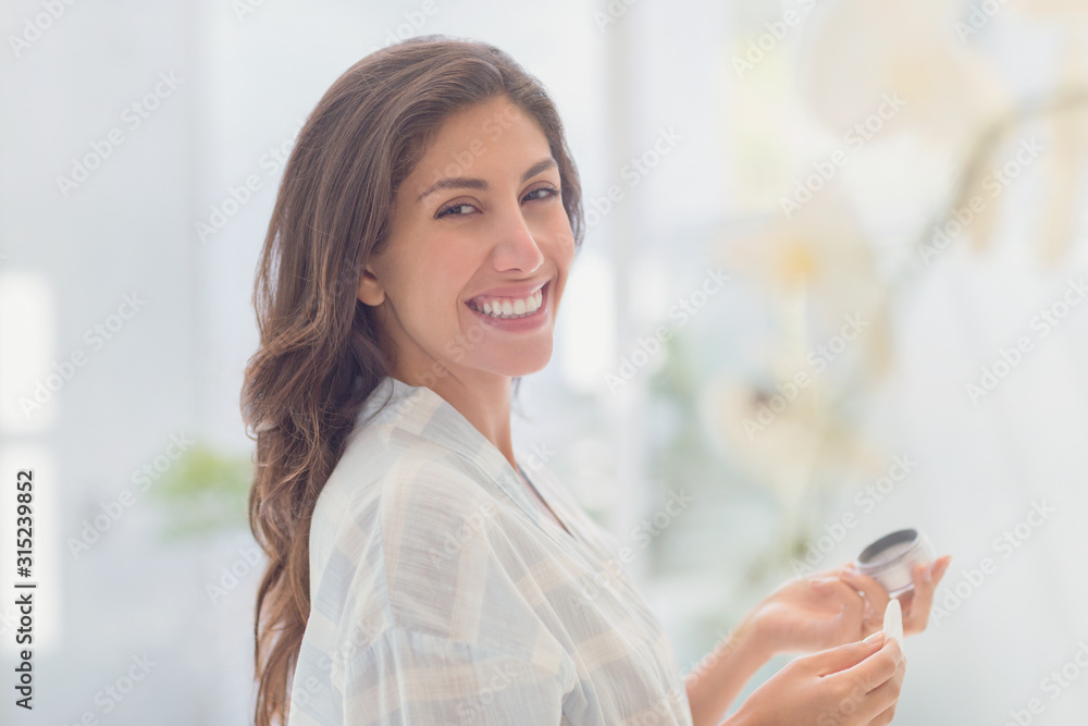 Portrait smiling brunette woman applying makeup