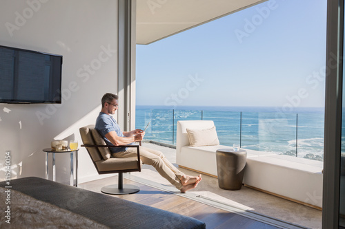 Man using digital tablet overlooking sunny ocean view
