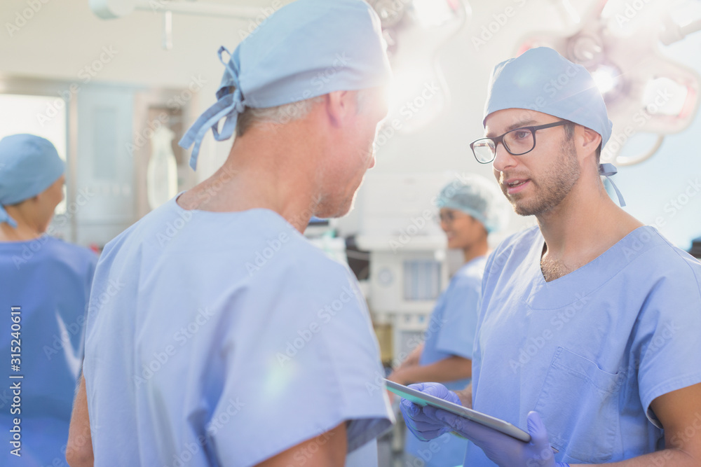 Male surgeons with digital tablet talking in operating room Male surgeons with digital tablet talking in operating room