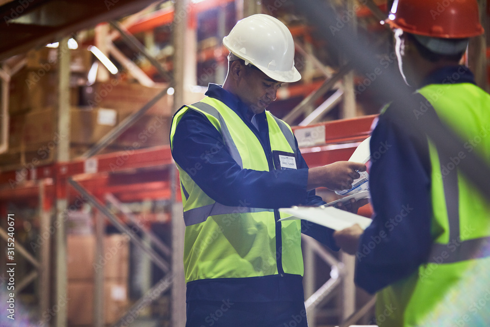 Workers with clipboards meeting in distribution warehouse Workers with clipboards meeting in distribution warehouse
