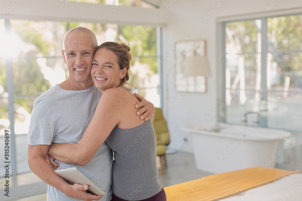 Portrait happy mature couple with digital tablet hugging in bedroom Portrait happy mature couple with digital tablet hugging in bedroom