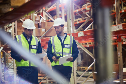 Workers with clipboards and scanner in distribution warehouse
