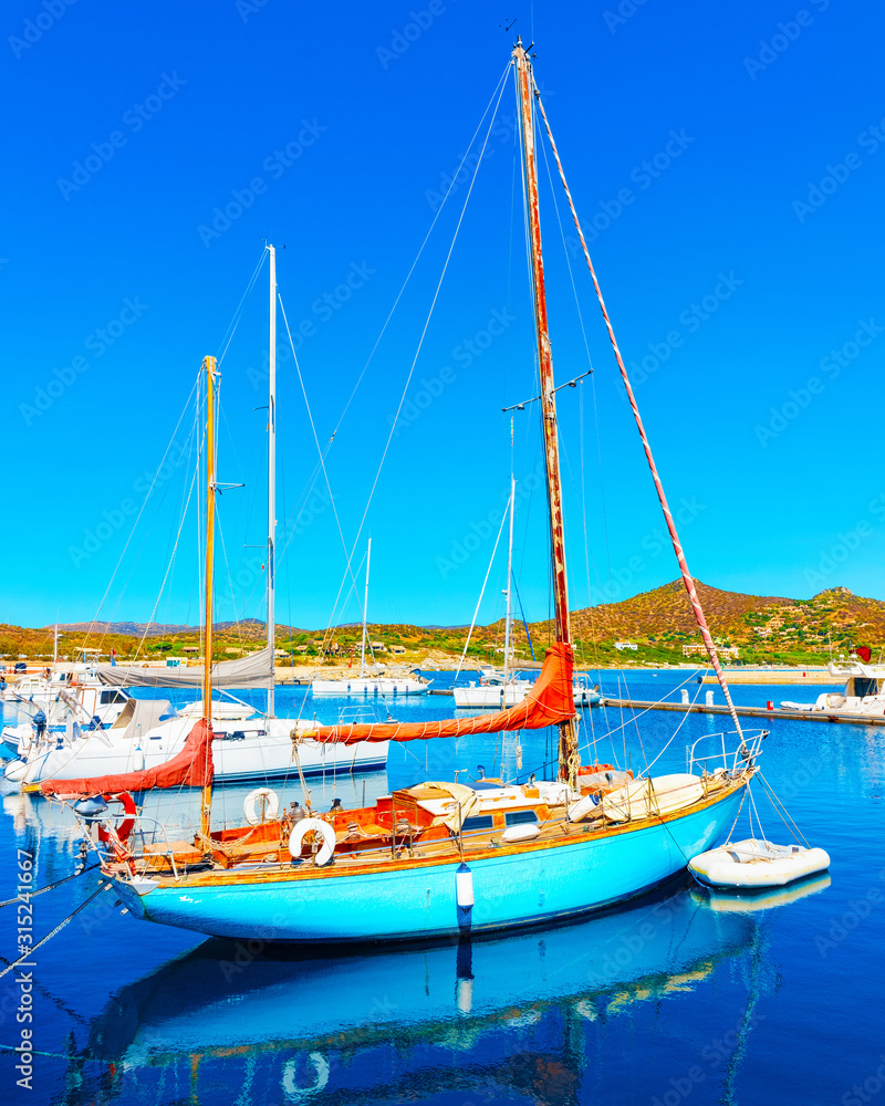 Old Sardinian Port and marina with ships at Mediterranean Sea in city of Villasimius in South Sardinia Island Italy in summer. Cityscape with Yachts and boats