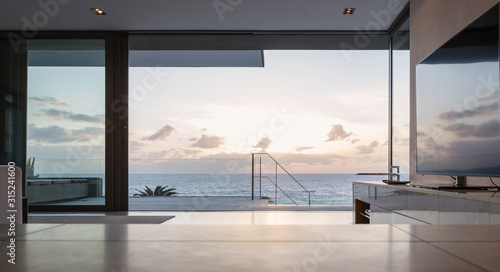 Home showcase living room and patio with tranquil sunset ocean view
