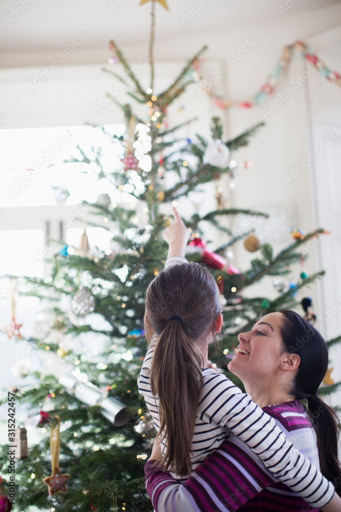 Affectionate mother and daughter looking up at Christmas tree Affectionate mother and daughter looking up at Christmas tree