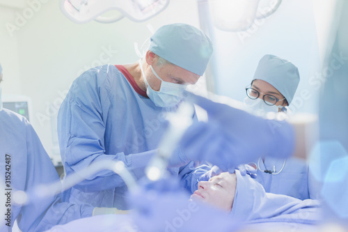 Surgeons operating on female patient in operating room