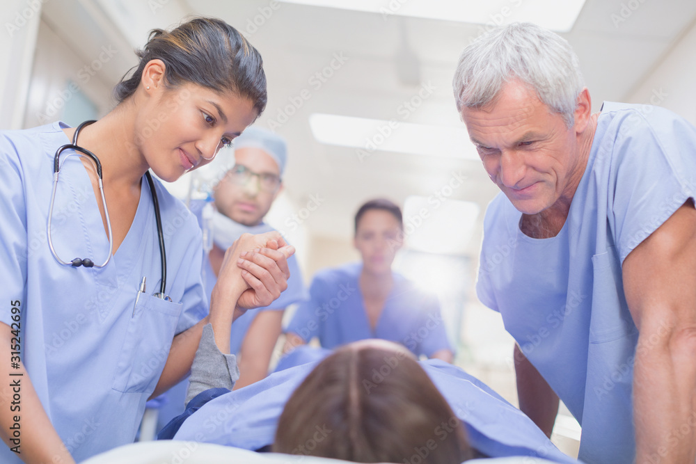 Caring surgeons talking to patient on stretcher in hospital corridor Caring surgeons talking to patient on stretcher in hospital corridor