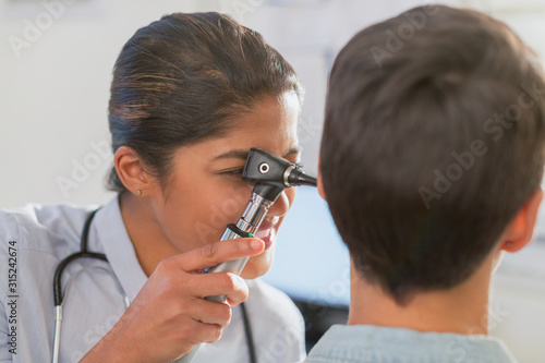Female doctor using otoscope in ear of patient