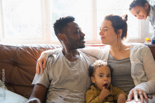 Affectionate multi-ethnic young family on living room sofa photo