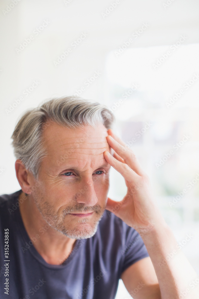 Tired mature man holding head in hand at bathroom mirror Tired mature man holding head in hand at bathroom mirror
