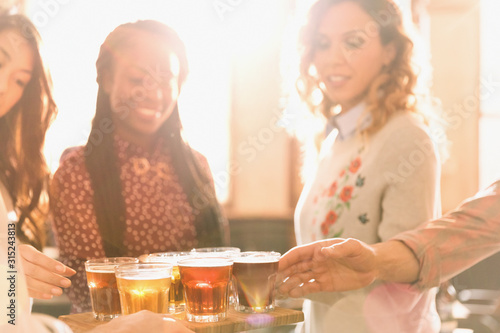 Women friends sampling beer at microbrewery bar