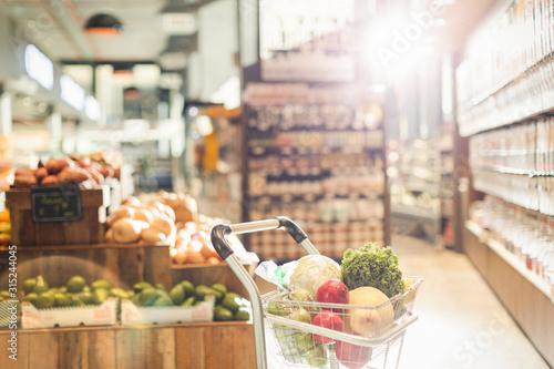 Fresh produce in shopping cart in grocery store market photo