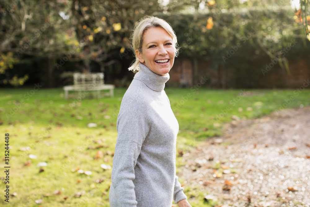 Portrait smiling, confident mature woman in sunny autumn backyard Portrait smiling, confident mature woman in sunny autumn backyard