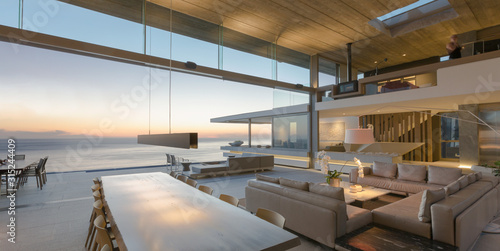 Modern, luxury home showcase living room and dining room open to ocean view at dusk photo