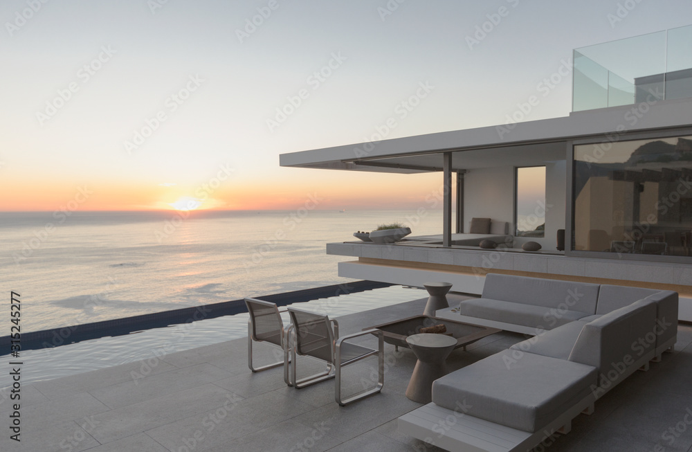View of sunset over ocean horizon from modern, luxury home showcase exterior patio View of sunset over ocean horizon from modern, luxury home showcase exterior patio