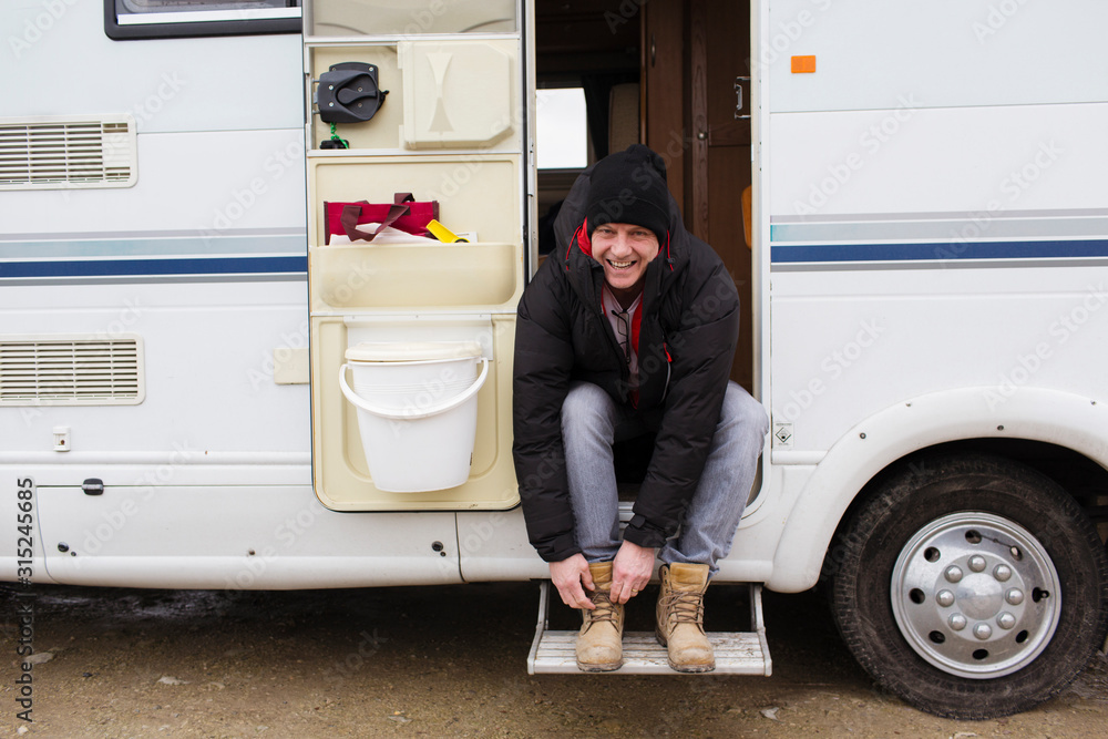 Portrait smiling man tying boot shoelaces in motor home doorway Portrait smiling man tying boot shoelaces in motor home doorway