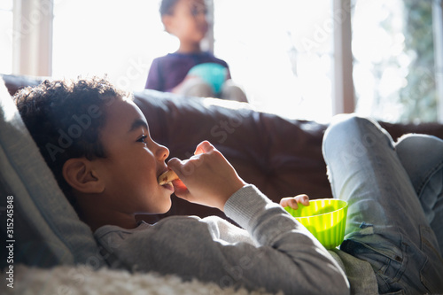 Boy eating snack and watching TV on sofa