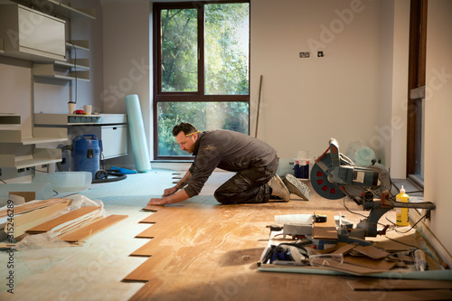 Construction worker laying hardwood flooring in house