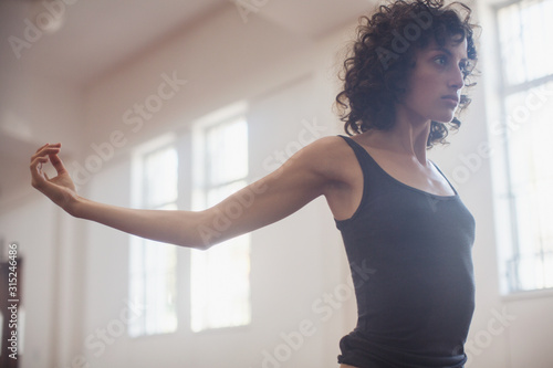 Focused, determined young female dancer stretching in dance studio