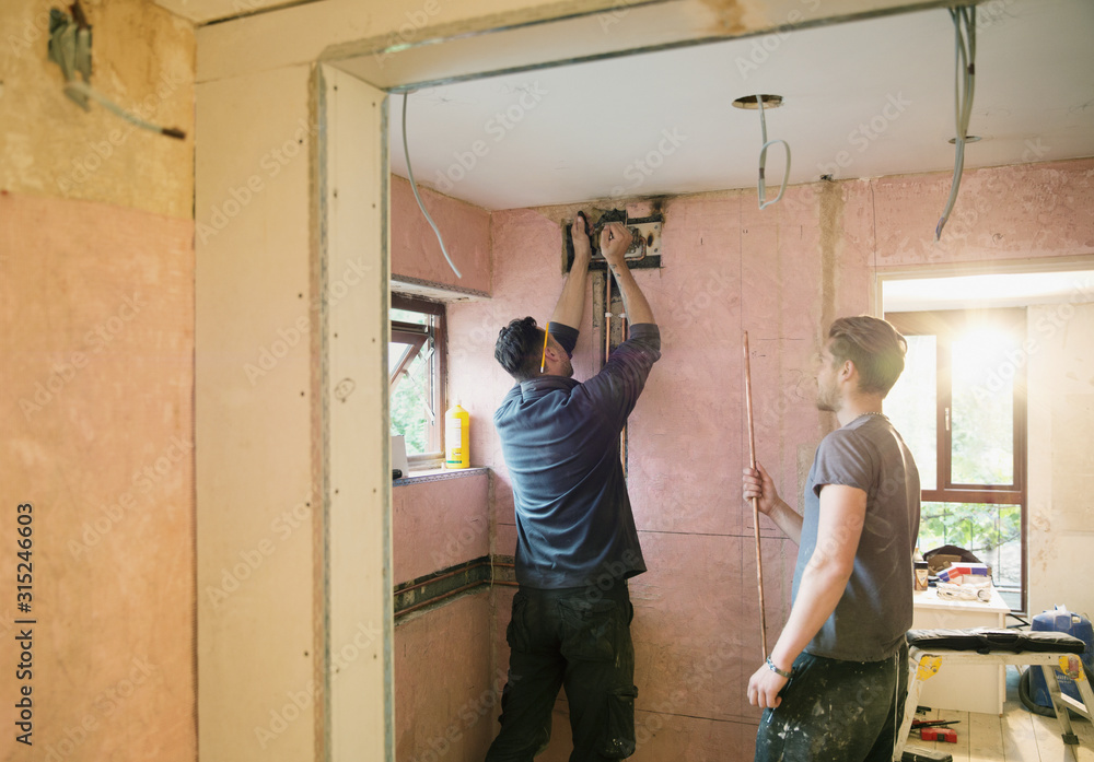 Construction workers installing copper pipe in house Construction workers installing copper pipe in house