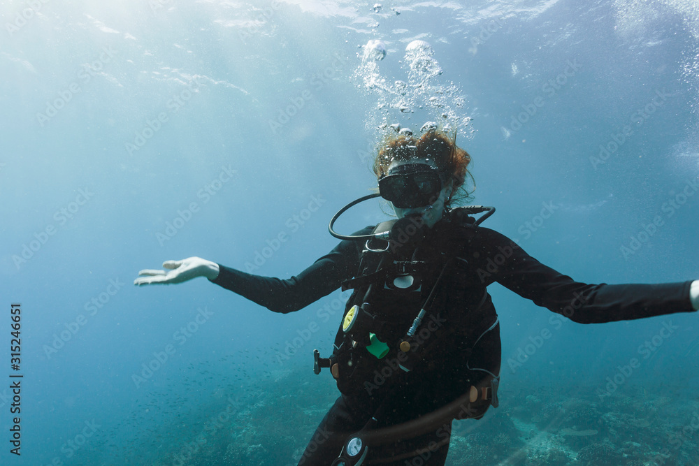 Portrait young woman scuba diving underwater with arms outstretched Portrait young woman scuba diving underwater with arms outstretched