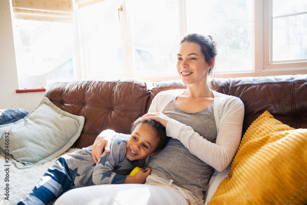 Affectionate mother and toddler son cuddling on living room sofa Affectionate mother and toddler son cuddling on living room sofa