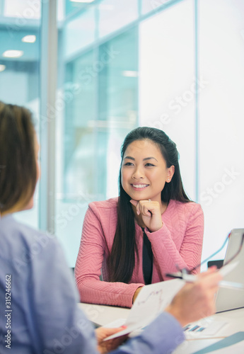 Smiling, attentive businesswoman listening to colleague in meeting